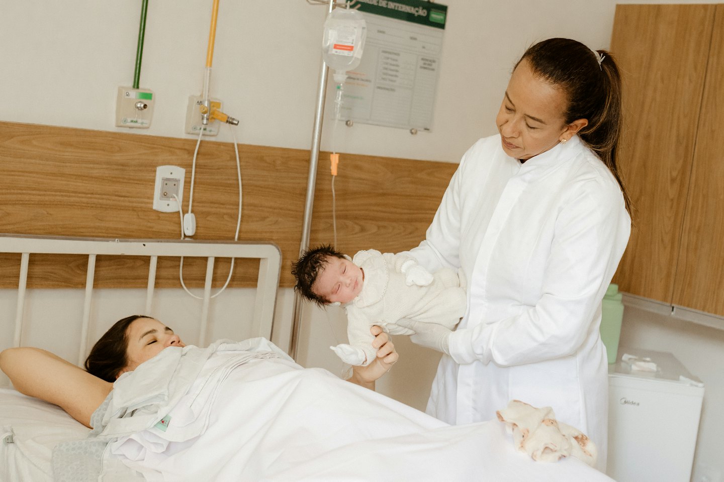 A healthcare worker presents a newborn baby to a mother.