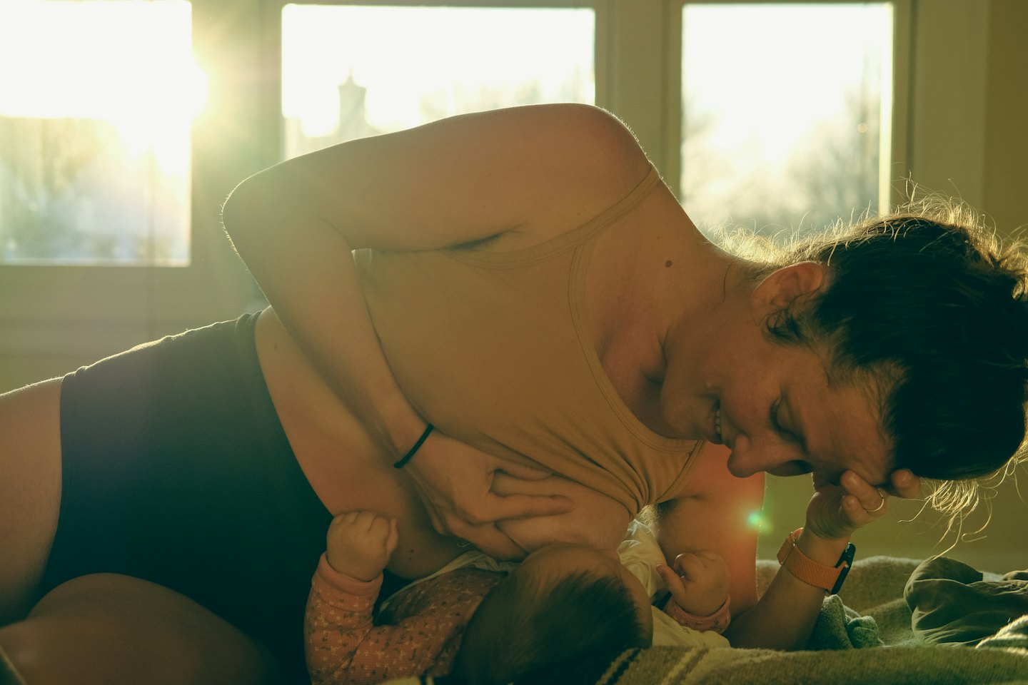 Mother breastfeeding her baby indoors.